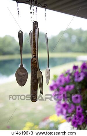 Stock Image - antique silverware wind chime hangs on porch of country home. Fotosearch