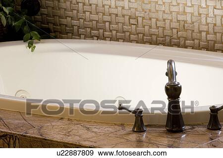 Stock Photo - Bronze faucet and Jacuzzi tub. Fotosearch