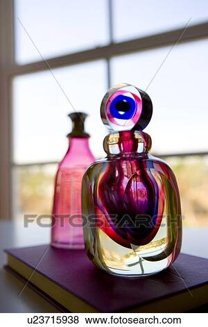 Stock Photo - Colorful decorative jars on book in front of window. Fotosearch