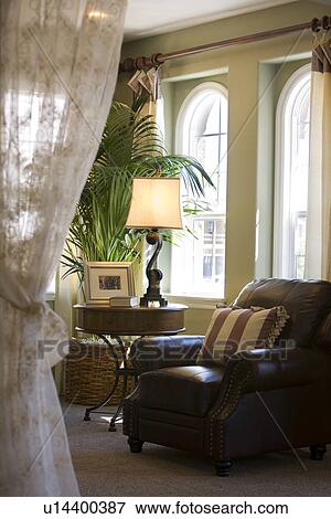 Stock Photo - Comfy brown leather armchair in front of windows. Fotosearch