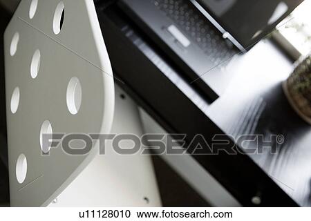 Stock Image - Contemporary white desk chair by black desk with laptop. Fotosearch