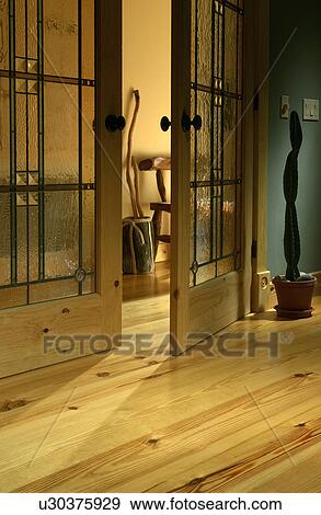 Stock Photo - Detail pine hardwood floors and open stained glass double doors. Fotosearch