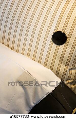 Stock Image - Detail striped pillow with button and comforter. Fotosearch