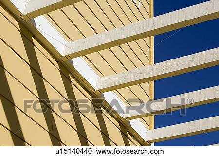 Stock Image - Detail yellow home with white trellis. Fotosearch