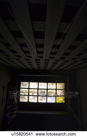Stock Image - Dirty stained glass window in basement. Fotosearch