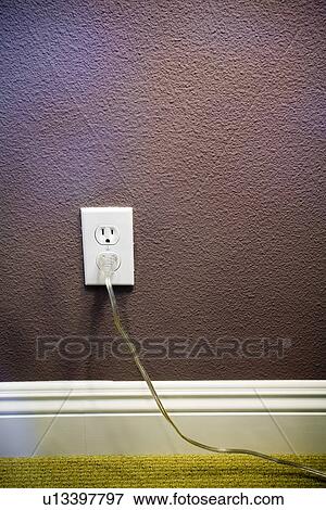 Stock Photo - Electrical outlet with plug on purple wall. Fotosearch
