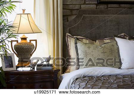 Elegant bed and nightstand in front of window View Large Photo Image Stock Image - Elegant bed and nightstand in front of window. Fotosearch