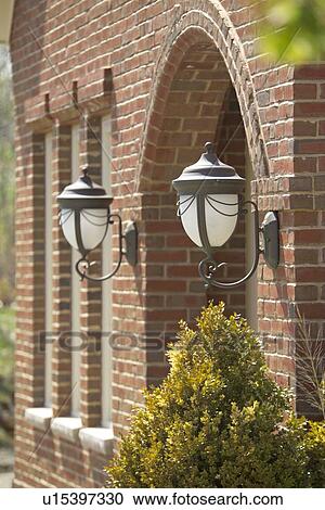 Stock Image - Exterior wall lights on brick home. Fotosearch