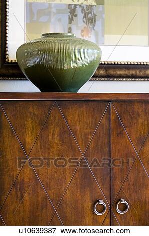 Stock Photo - Green decorative vase on wooden cabinet. Fotosearch