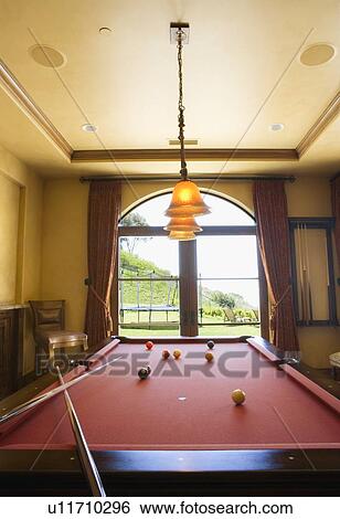 Stock Photograph - Red Pool Table and Balls with Overhead Lights and Window. Fotosearch
