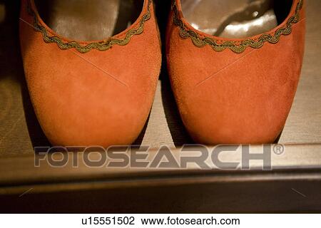 Stock Image - Red suede shoes on wooden shelf. Fotosearch