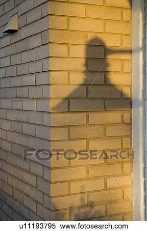 Stock Photography - Shadow of exterior lighting fixture on brick wall. Fotosearch