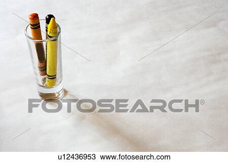 Stock Image - Shot glass with crayons on table. Fotosearch