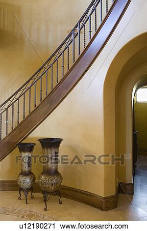 Stock Image - Staircase Over Archway with Decorative Metal Vase. Fotosearch