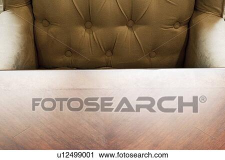 Stock Image - Suede armchair behind wooden table. Fotosearch