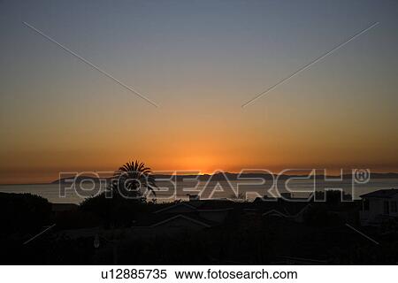 Sun setting in ocean behind housing community View Large Photo Image Stock Photography - Sun setting in ocean behind housing community. Fotosearch
