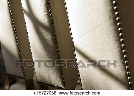 Stock Photo - Sunlight streaming over back of dining room chairs. Fotosearch