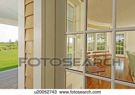 Stock Image - View from outside into sunroom with row of wooden benches. Fotosearch