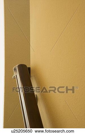 Stock Image - Wooden hand rail on yellow wall. Fotosearch