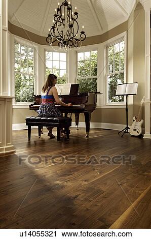 Stock Image - Young woman playing a grand piano. Fotosearch