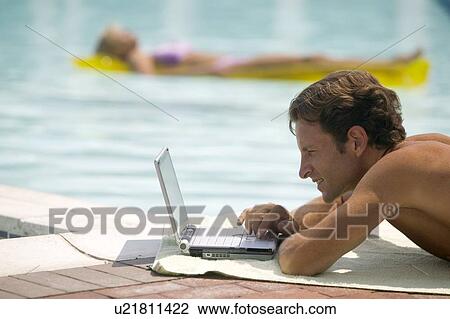 A man poolside using a laptop computer View Large Photo Image Stock Image - A man poolside using a laptop computer. Fotosearch
