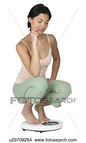 A woman weighing herself on a scale View Large Photo Image Picture - A woman weighing herself on a scale. Fotosearch