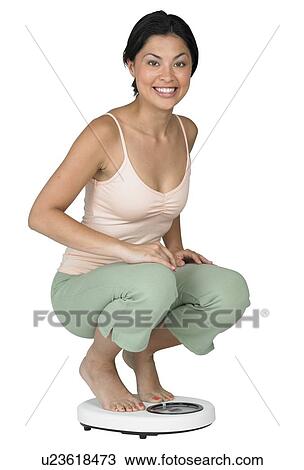 Stock Image - A woman weighing herself on a scale. Fotosearch