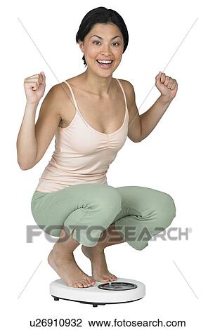 Stock Image - A woman weighing herself on a scale. Fotosearch