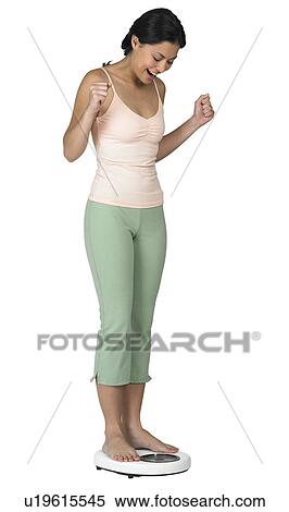 Stock Photography - A woman weighing herself on a scale. Fotosearch