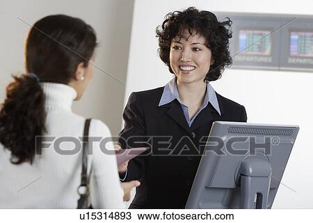 Airline employee assisting a customer at ticket counter View Large Photo Image Stock Image - Airline employee assisting a customer at ticket counter. Fotosearch