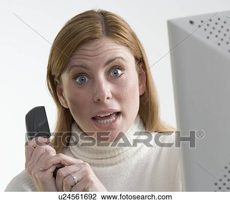 Stock Image - Annoyed woman with phone and computer. Fotosearch
