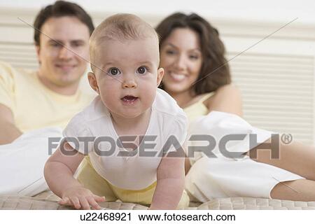 Baby crawling on bed with parents View Large Photo Image Stock Image - Baby crawling on bed with parents. Fotosearch