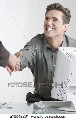 Businessman at desk shaking hands View Large Photo Image Stock Image - Businessman at desk shaking hands. Fotosearch