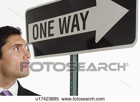 Businessman looking at one way sign View Large Photo Image Stock Photography - Businessman looking at one way sign. Fotosearch