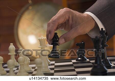Stock Photography - Businessman moving chess piece. Fotosearch