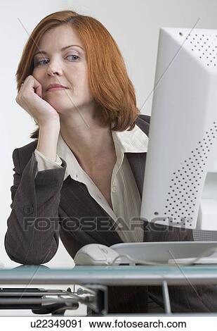 Stock Image - Businesswoman looking askance at her computer. Fotosearch