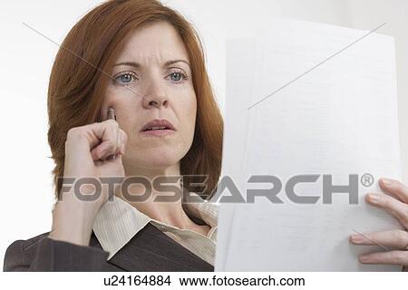 Businesswoman reading papers thoughtfully View Large Photo Image Picture - Businesswoman reading papers thoughtfully. Fotosearch