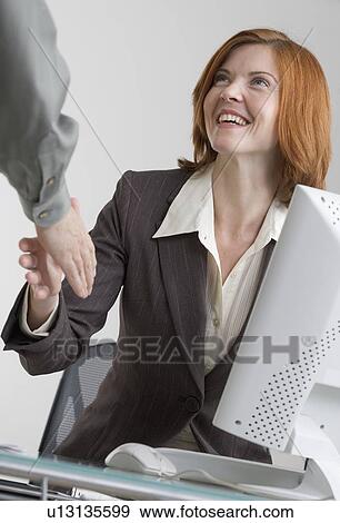 Stock Photo - Businesswoman shaking hands with colleague. Fotosearch