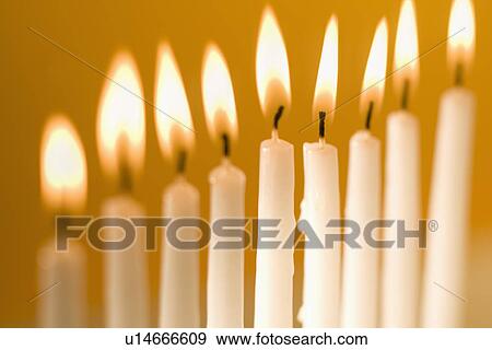 Stock Photo - Candles burning in a menorah. Fotosearch