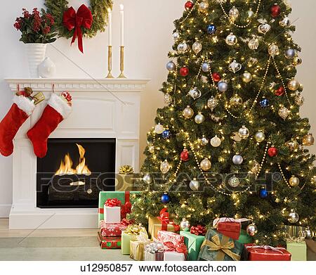 Stock Photo - Christmas tree with presents and fireplace with stockings. Fotosearch