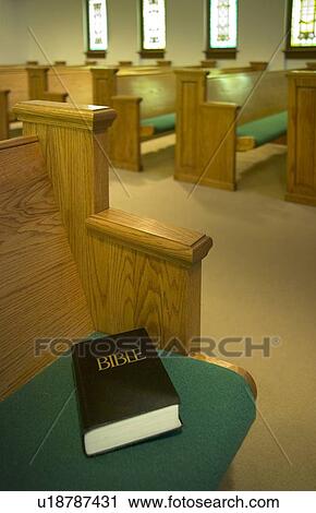 Stock Image - Church interior with Bible on a pew. Fotosearch