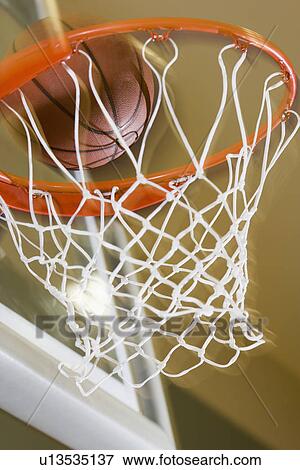 Stock Photo - Close up of basketball entering hoop. Fotosearch