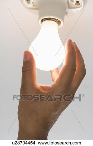 Picture - Close up of lightbulb being screwed in . Fotosearch