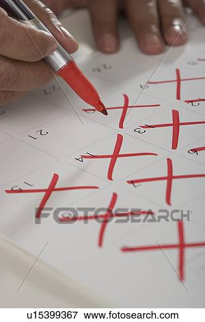 Close up of man crossing out days on calendar View Large Photo Image Stock Photo - Close up of man crossing out days on calendar. Fotosearch