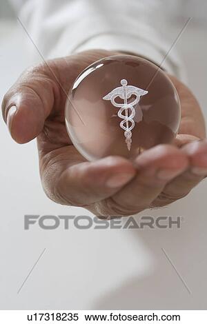 Stock Photography - Close up of man holding clear ball with Caduceus symbol. Fotosearch