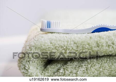 Stock Photo - Close up of toothbrush on folded towel. Fotosearch