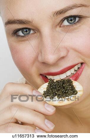 Close up of woman eating caviar on a cracker View Large Photo Image Stock Image - Close up of woman eating caviar on a cracker. Fotosearch