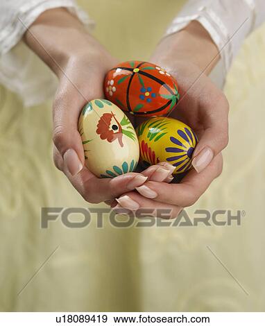 Stock Photo - Close up of woman's hands holding painted eggs. Fotosearch