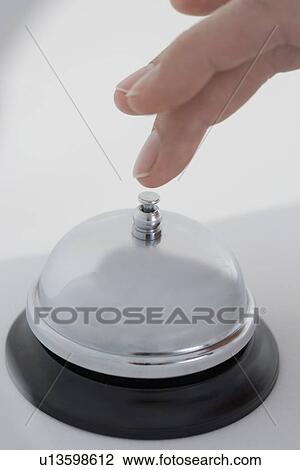 Stock Image - Closeup of finger ringing desk bell. Fotosearch