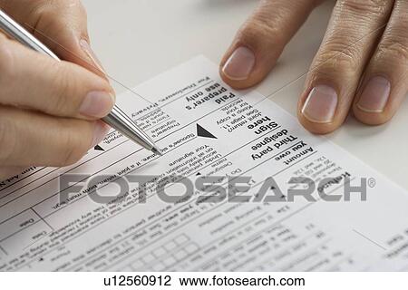 Stock Image - Closeup of hands with tax form. Fotosearch